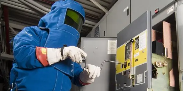 Trabajador con traje de protección contra arco eléctrico operando un tablero